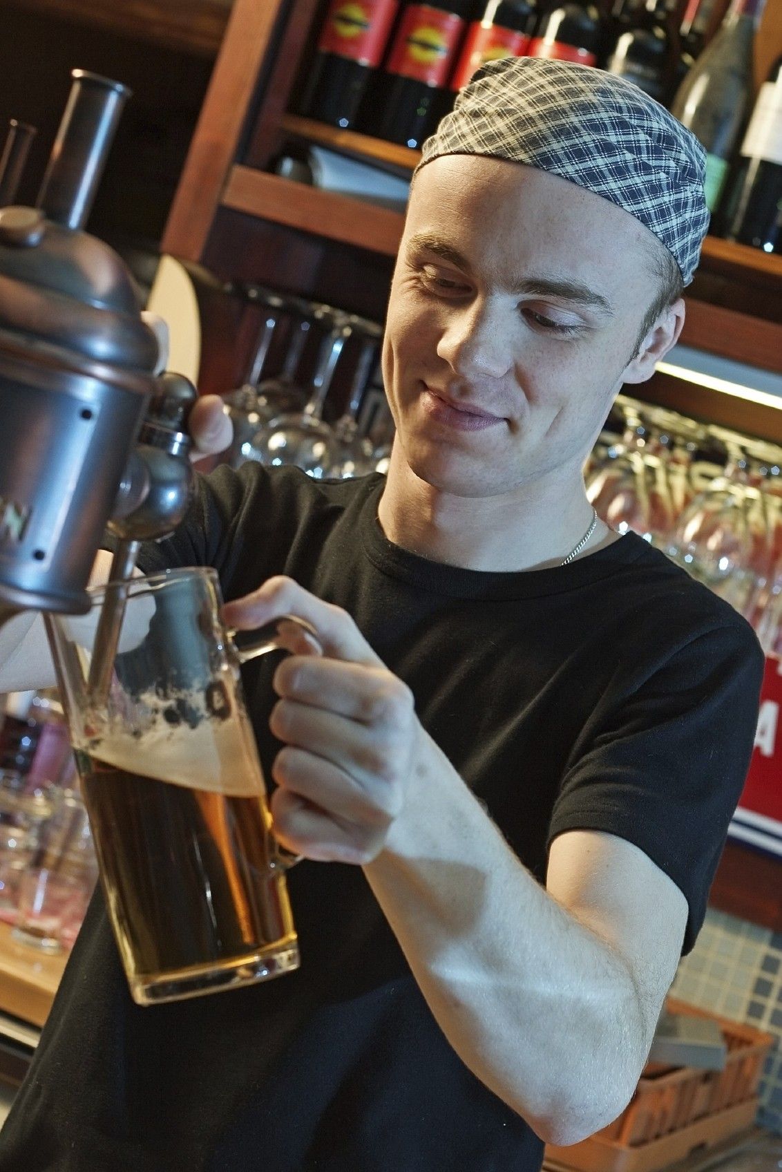 young man at a bar counter pouring beer